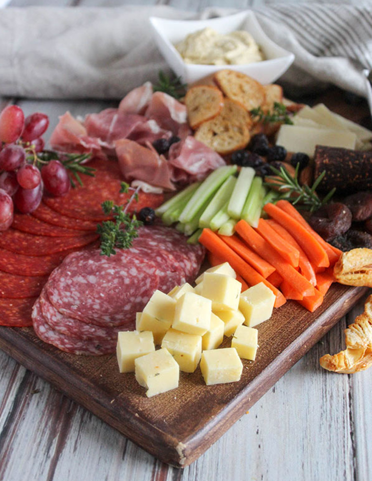 Simple and Savory displays, celery, carrots, meats, cheese, and grapes on their charcuterie board.
