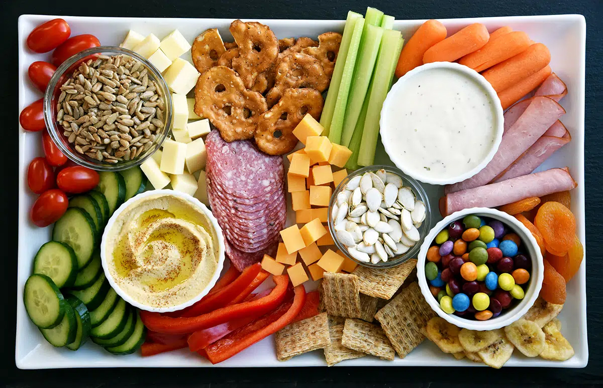 Whisking Mama presents pretzels, cucumbers, carrots, cheese, and meats on this kid friendly charcuterie board.