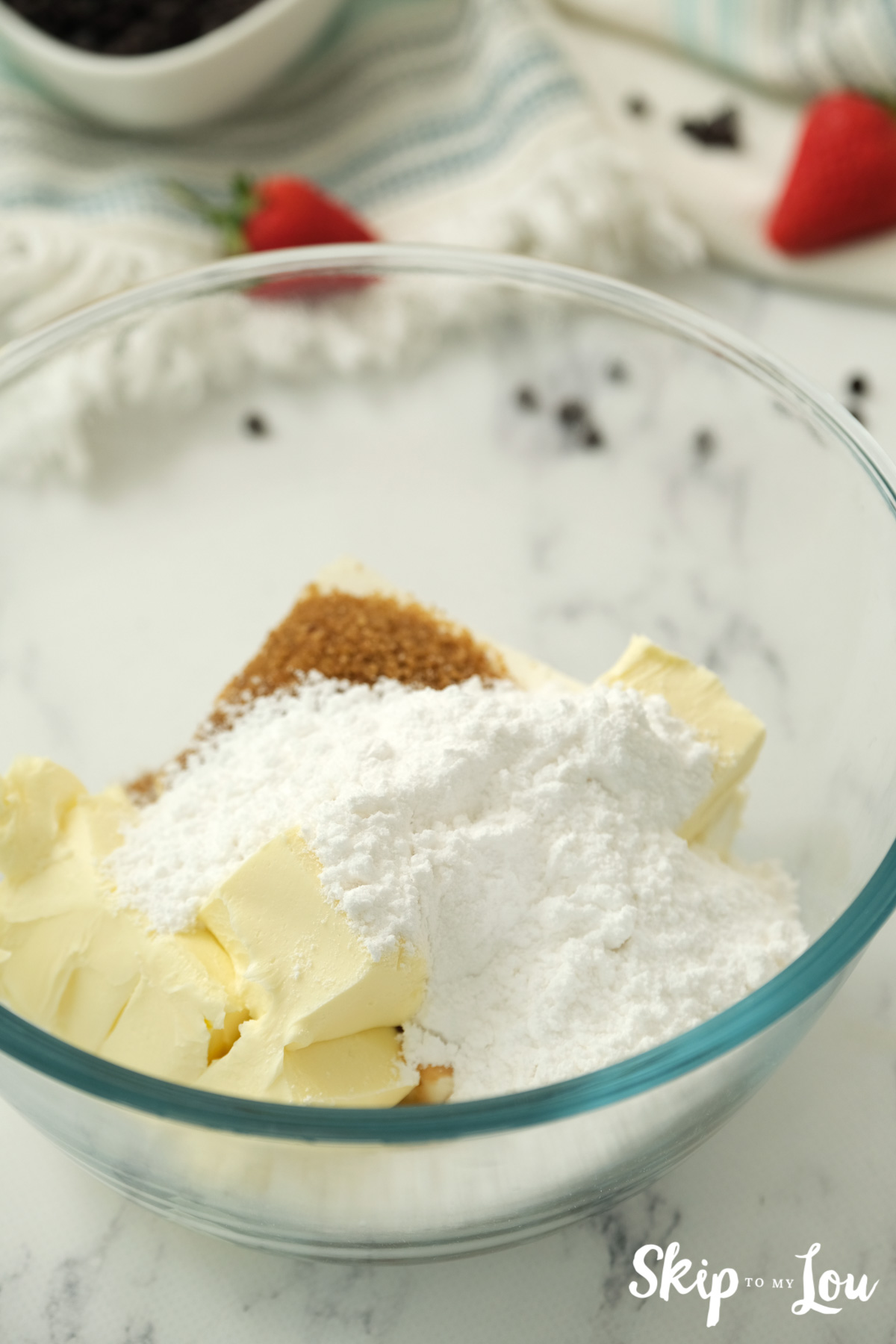 Butter, powdered sugar, cream cheese and brown sugar in a clear glass mixing bowl, by Skip to my Lou