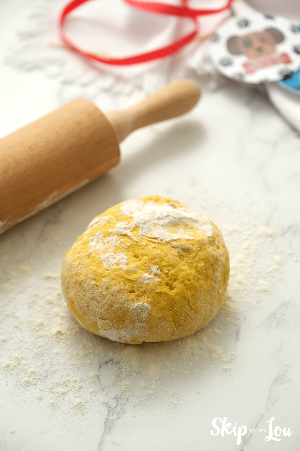 Dough for dog biscuits on a floured surface with a rolling pin, by Skip to my Lou.