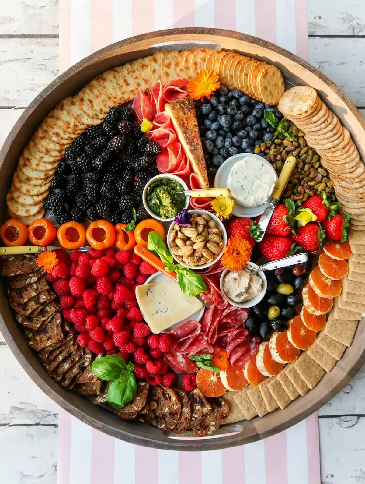 Reluctant entertainer created a large round board with crackers, blueberries, blackberries, meat, and more.