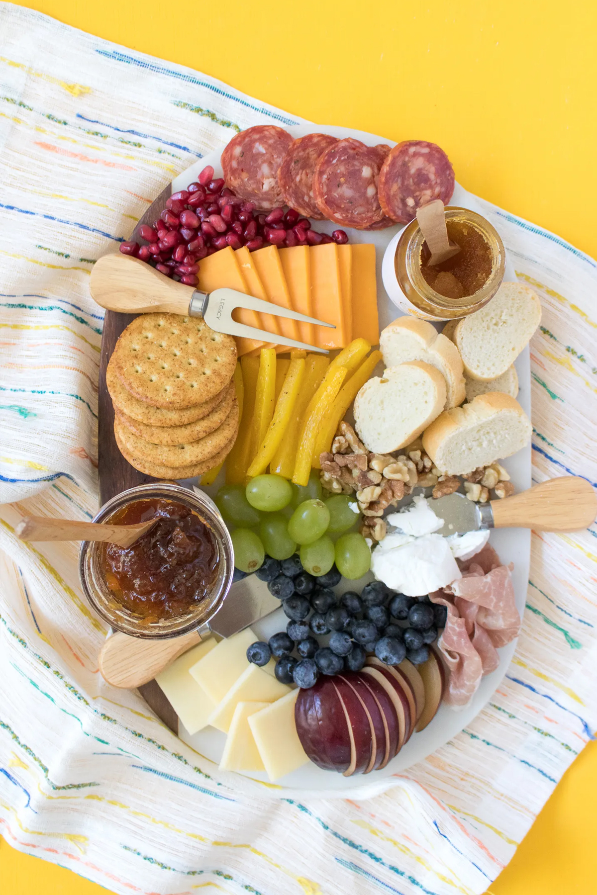 A small rainbow charcuterie board with breads, crackers, cheese, fruits, and jams from Sarah hearts.