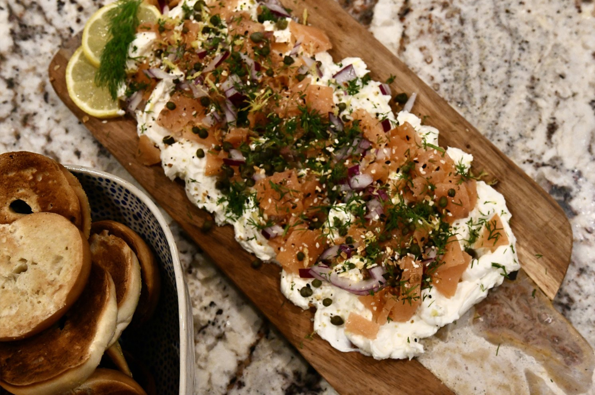 Cream cheese topped with salmon and seasoning and bagels fills Crazy Blonde Life's board.