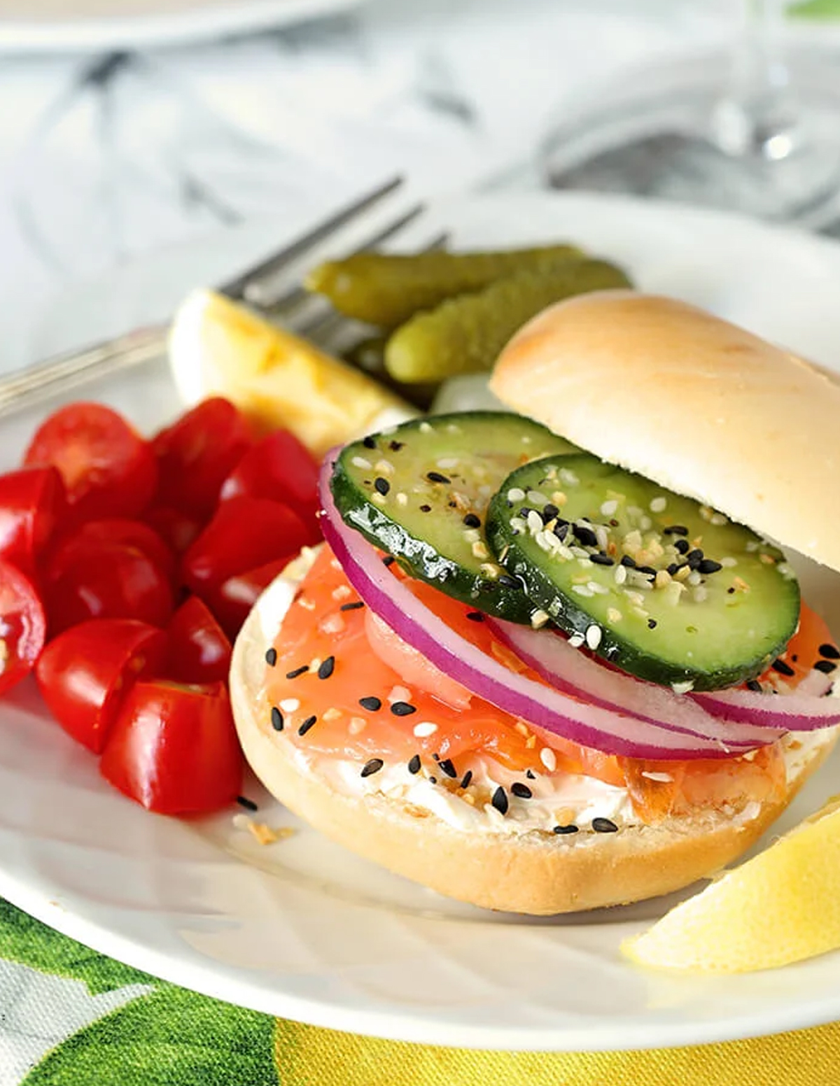 Creative Culinary bagel board is filled with cream cheese, salmon, pickles, onions, tomatoes, and bagels.