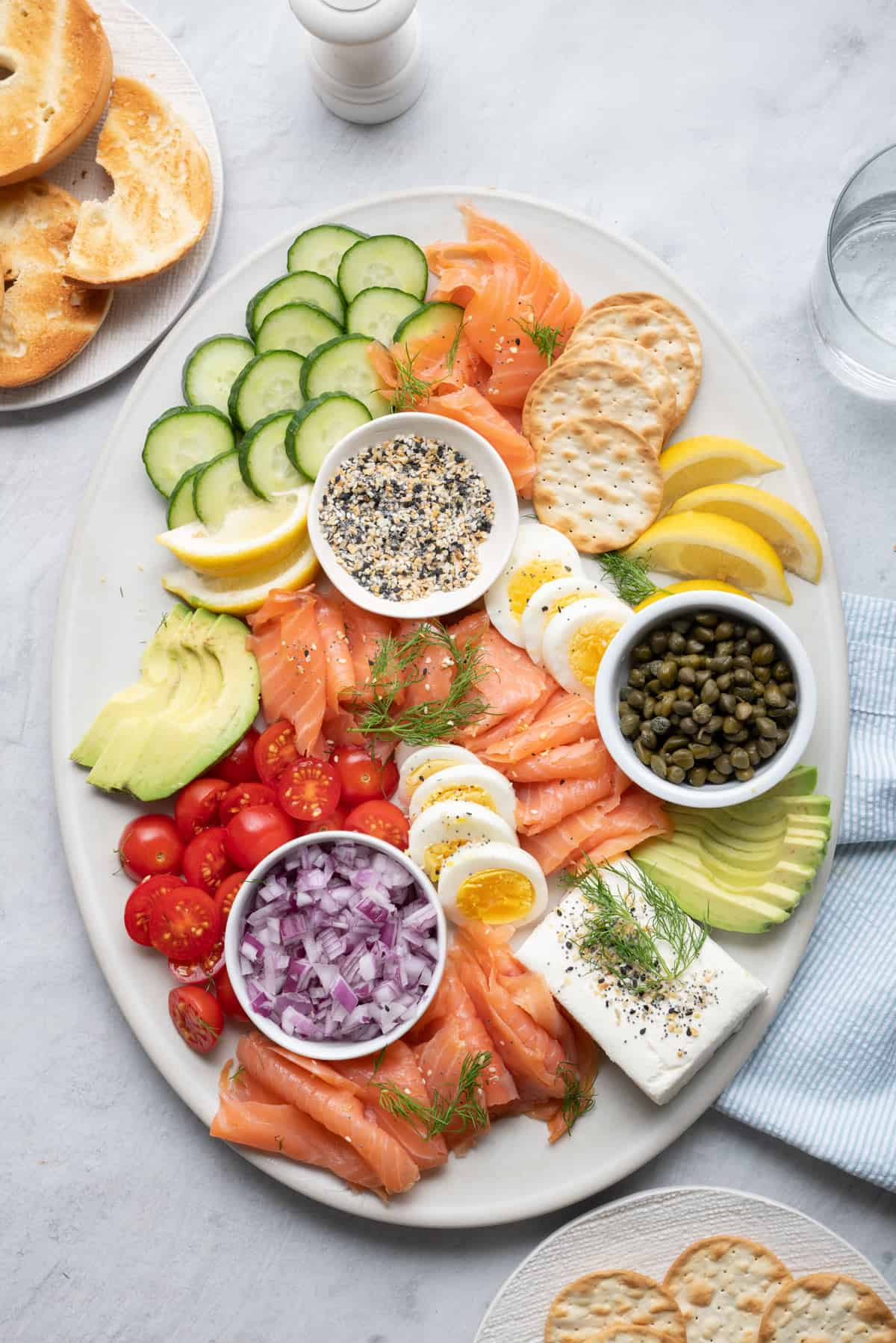 Feel Good Foodie's salmon board presents everything bagel seasoning, crackers, onions, tomatoes, avocado, cream cheese, eggs, and salmon.