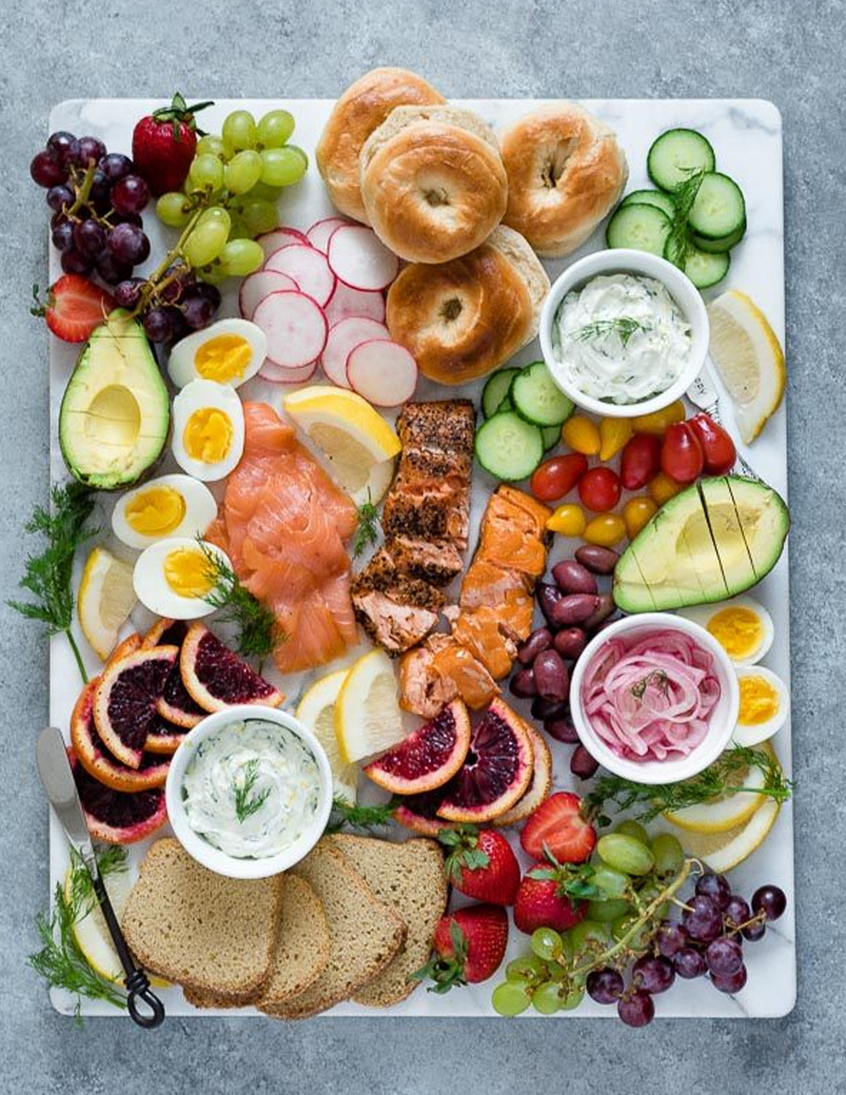 Flavor the Moment fills their board with bagels, grapes, tomatoes, salmon, avocado, and eggs.