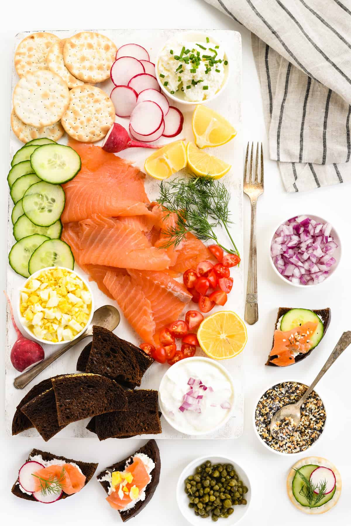 Spreads, cream cheese, capers, crackers, cucumbers, and salmon are included on Foxes Love Lemons salmon board.