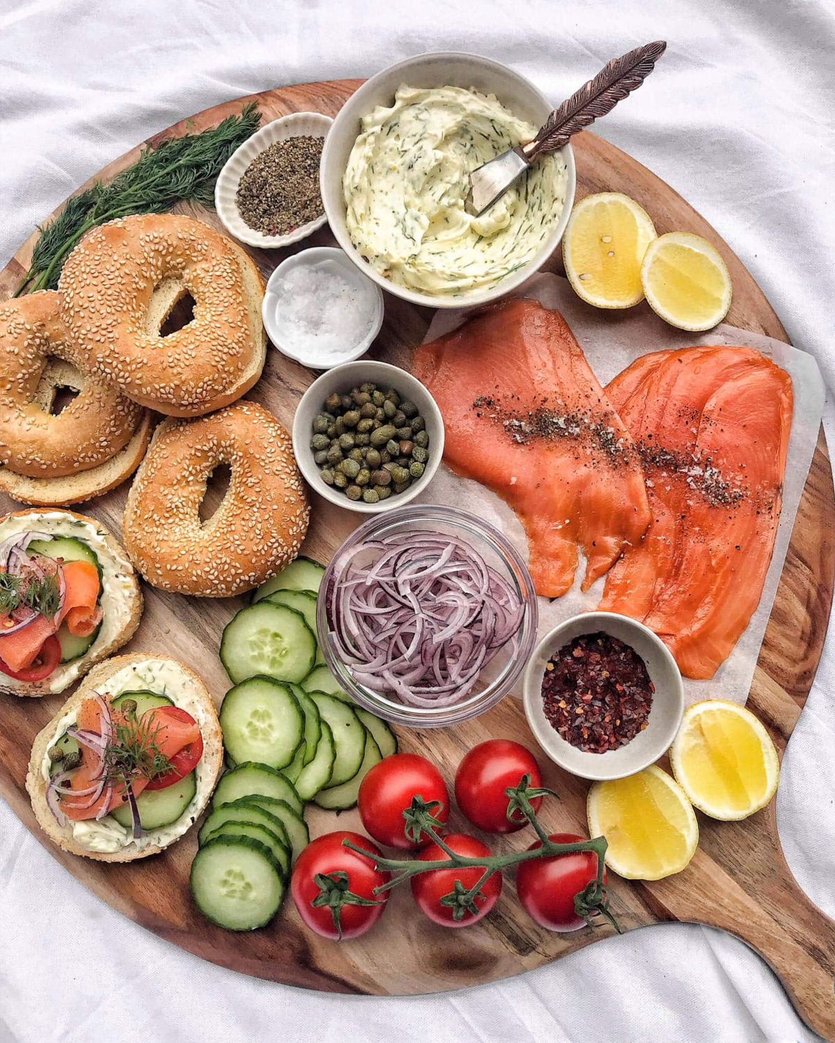 Nourish and Tempt's salmon bagel board is showcasing salmon, lemon dill cream cheese, and lemons.