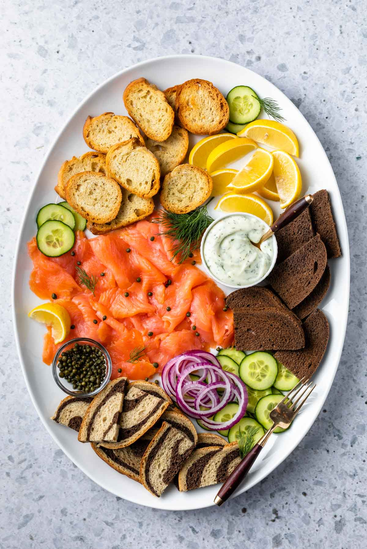 Simply Whisked  displays creamy cheese, smoked salmon, lemon, and bread on their salmon charcuterie board.