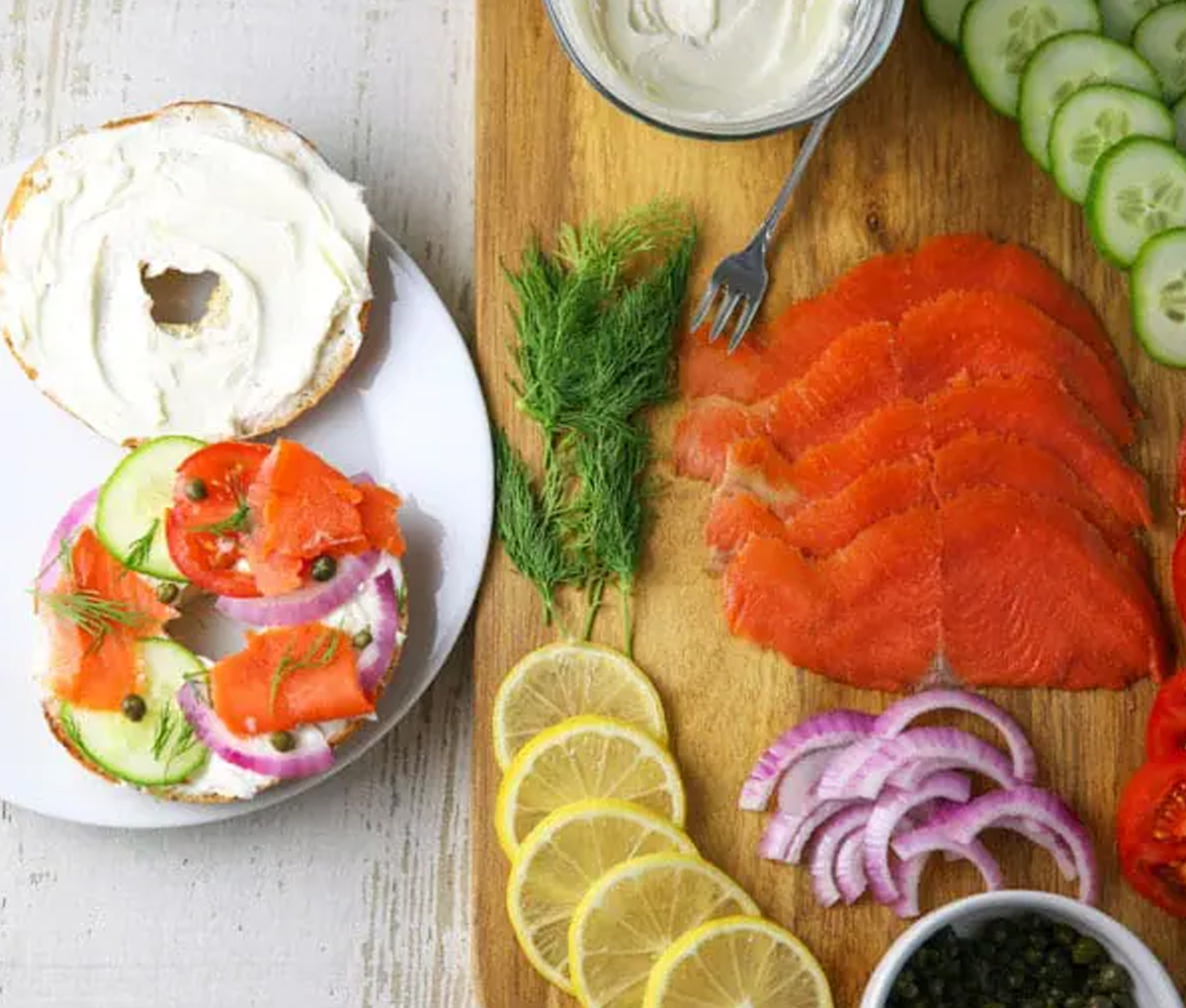 Bagels, salmon, lemon, onions, and soft cheese are displayed on Tasteful Venture's salmon brunch board.