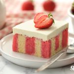 Red and White striped cake topped with smooth white icing and fresh strawberries, by Skip to my Lou.