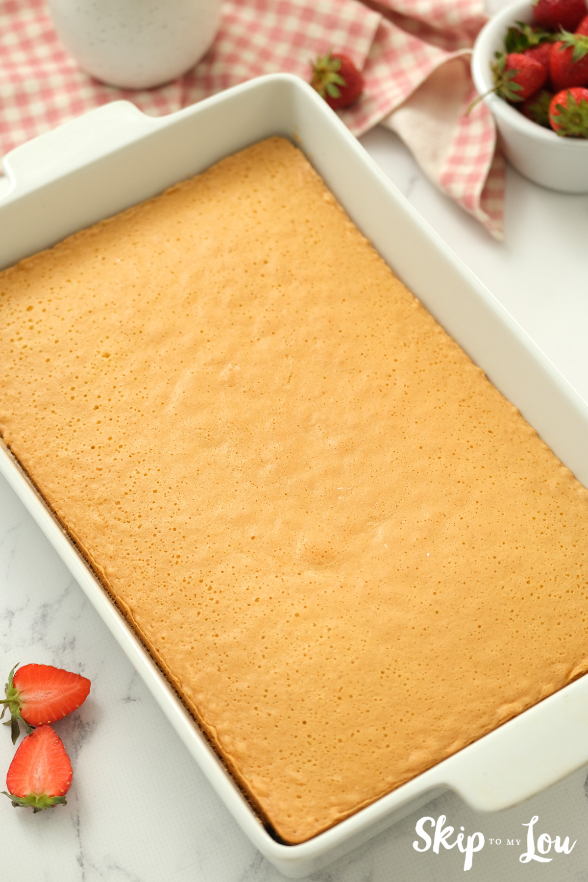 Golden brown cake baked in a white baking dish, by Skip to my Lou.