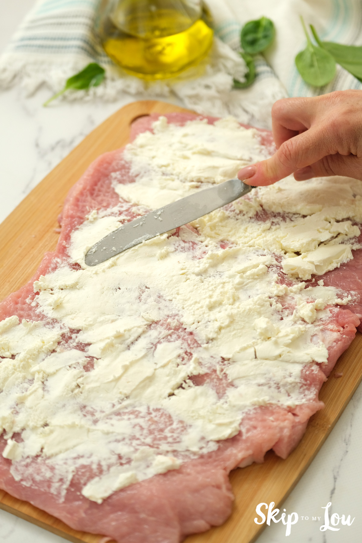 Pork loin with soften cream cheese spread on top with a knife, by Skip to my Lou.