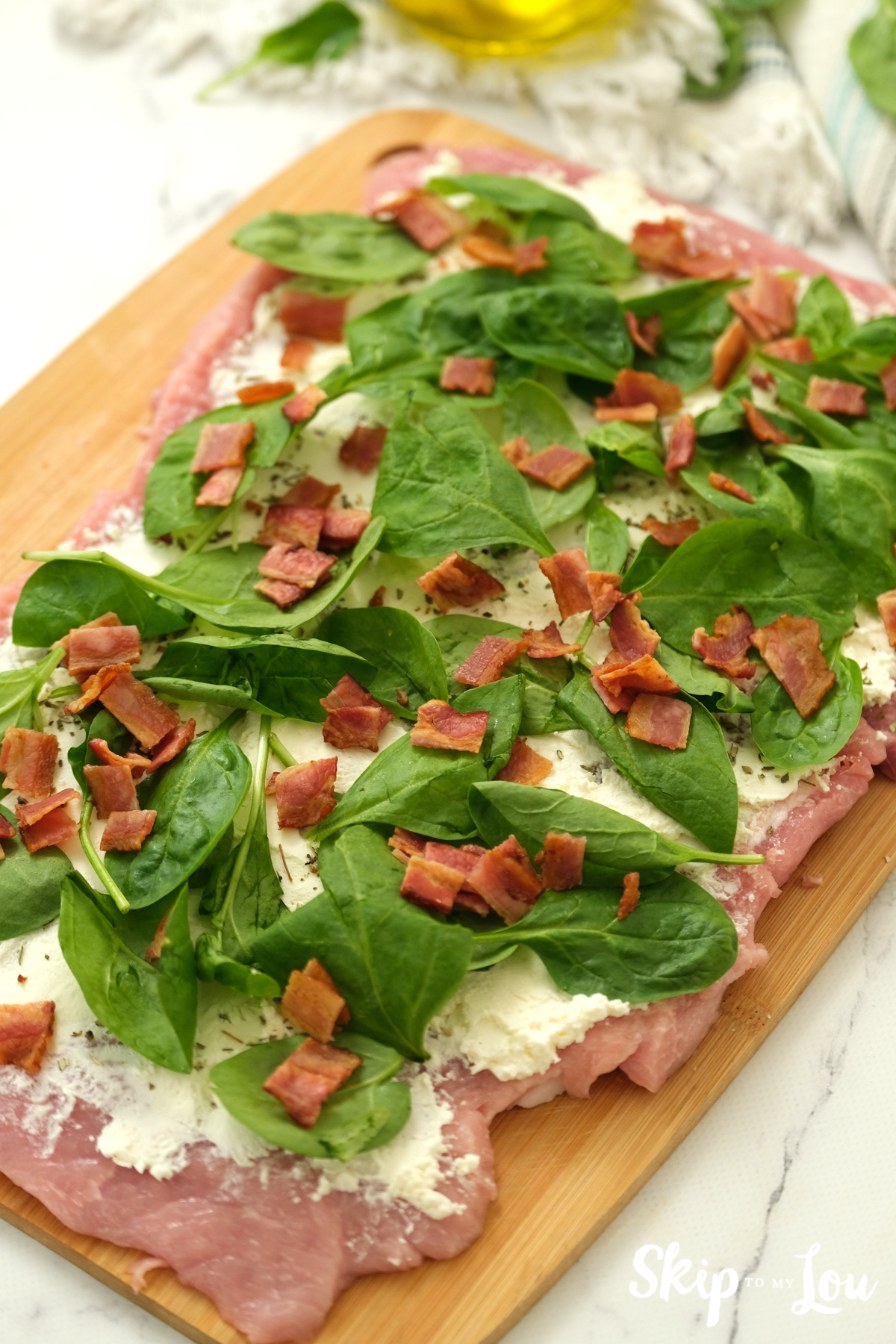 Pork loin with cream cheese, baby spinach and bacon on top, by Skip to my Lou.