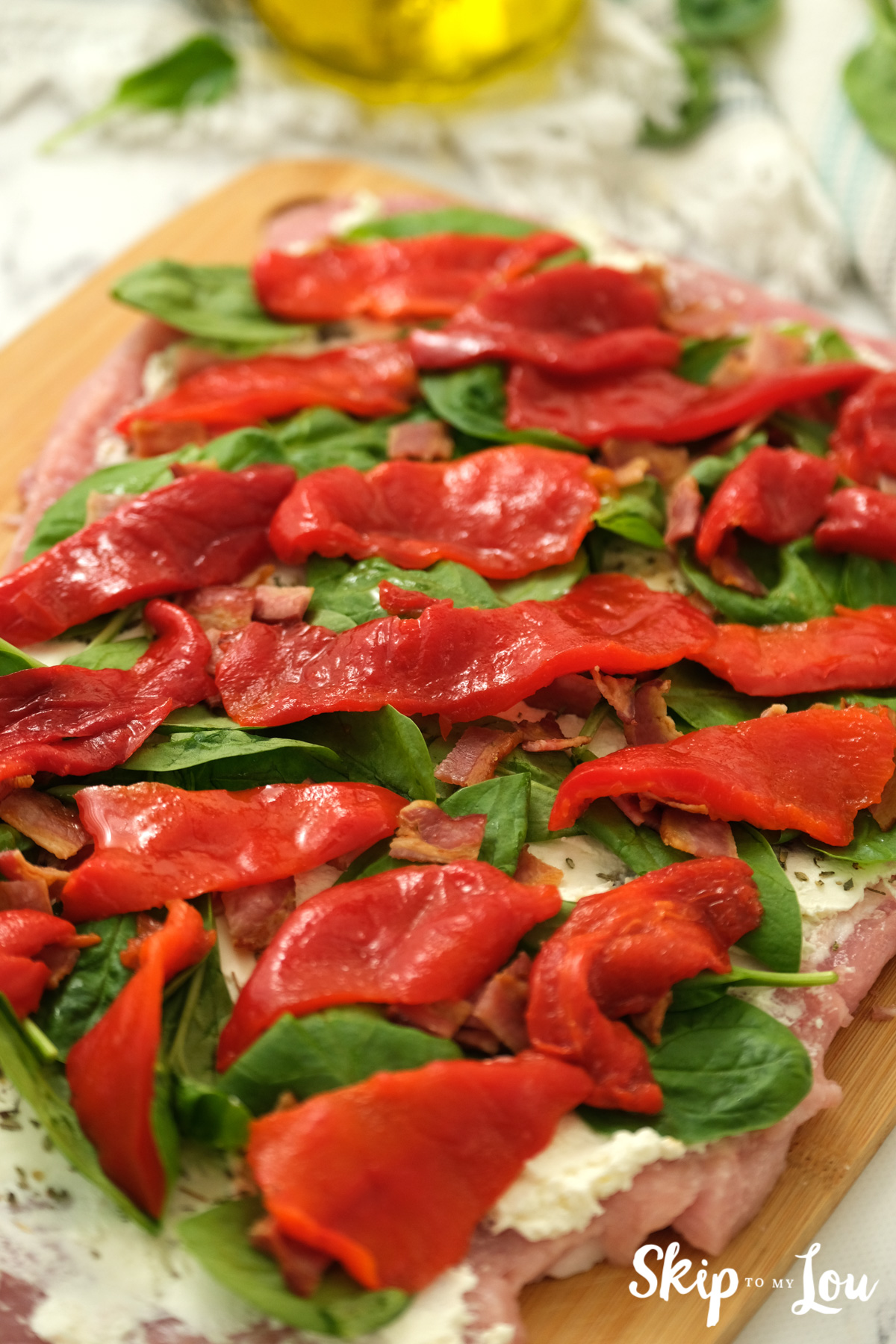 Pork loin with cream cheese, spinach, bacon and red peppers on top, by Skip to my Lou.
