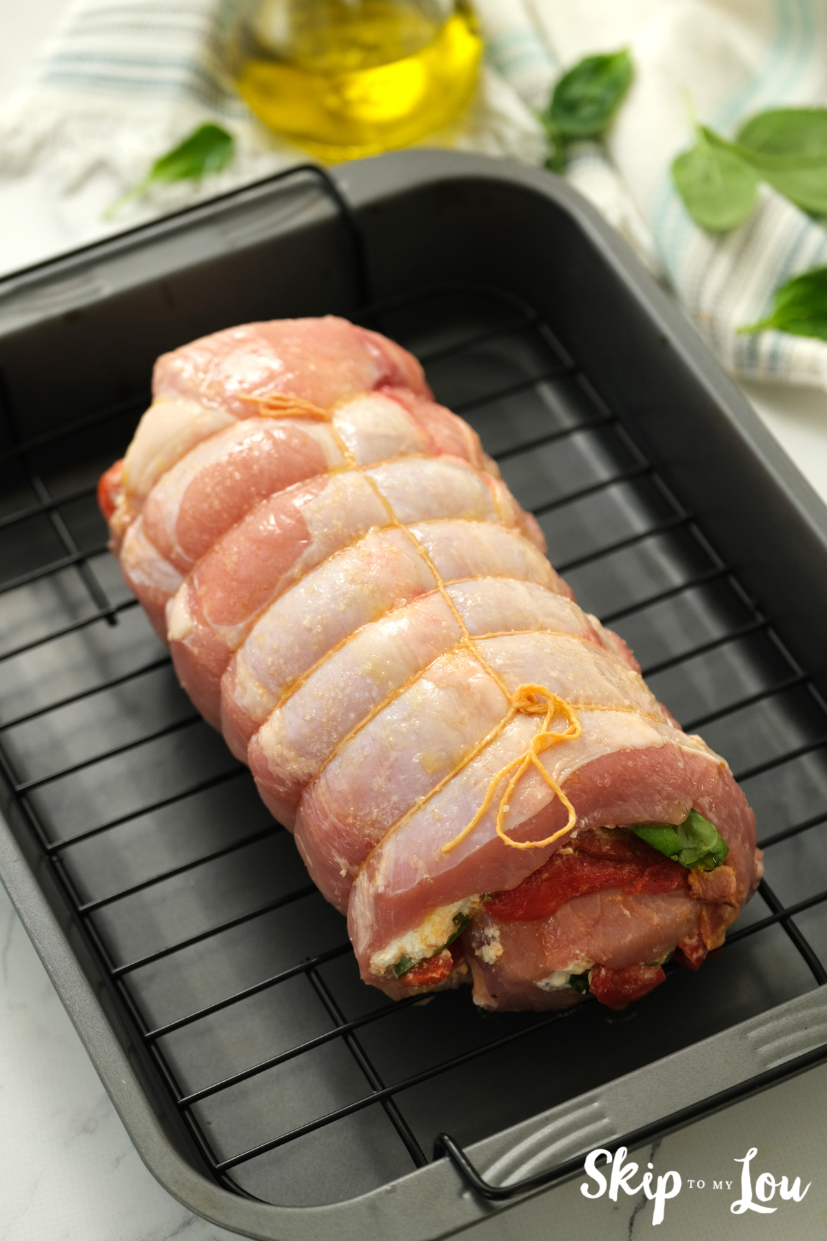 Stuffed pork loin sitting in a roasting pan ready to be cooked, by Skip to my Lou.