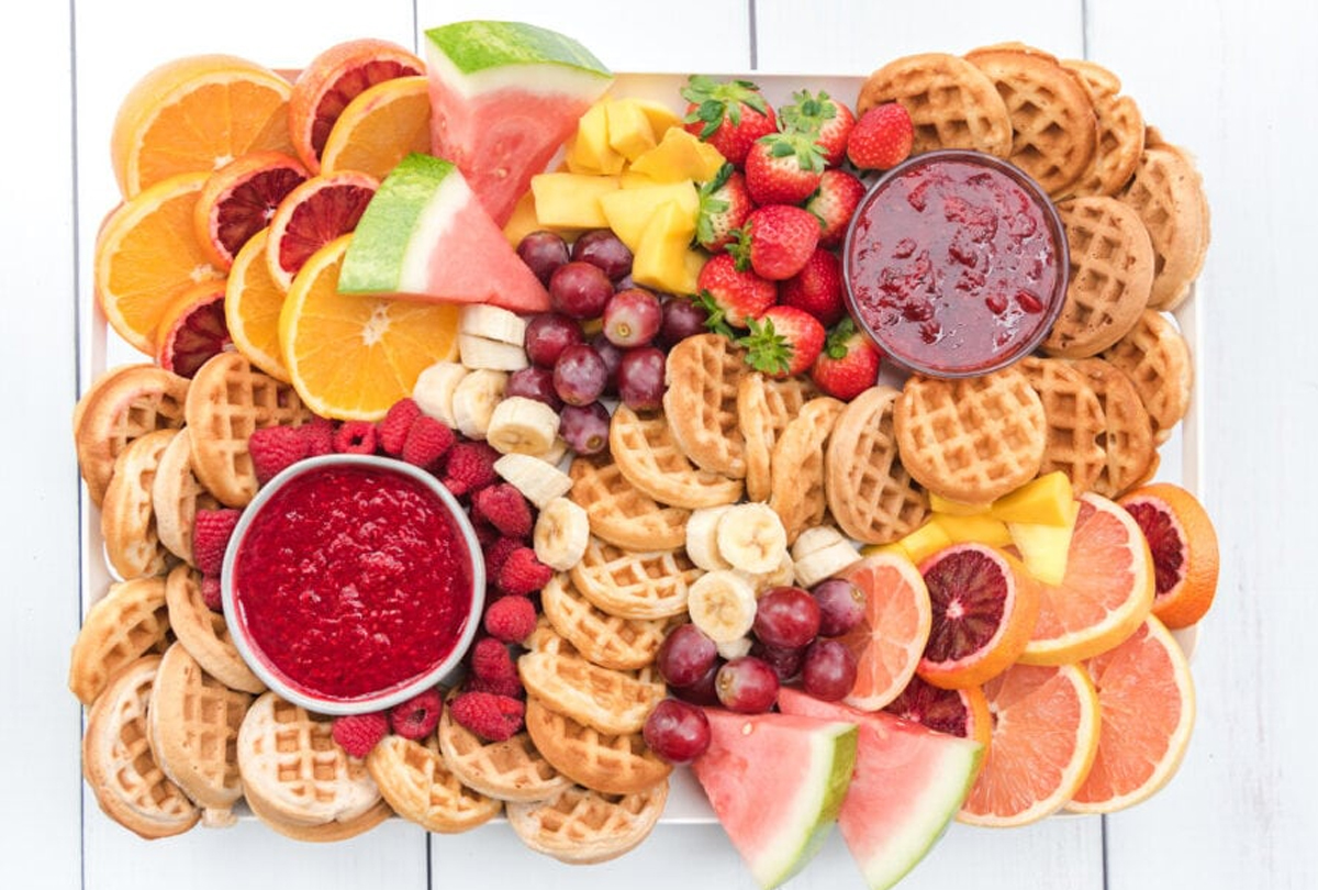 bright board full of red jams, mini waffles, and fruit from kitchen divas.