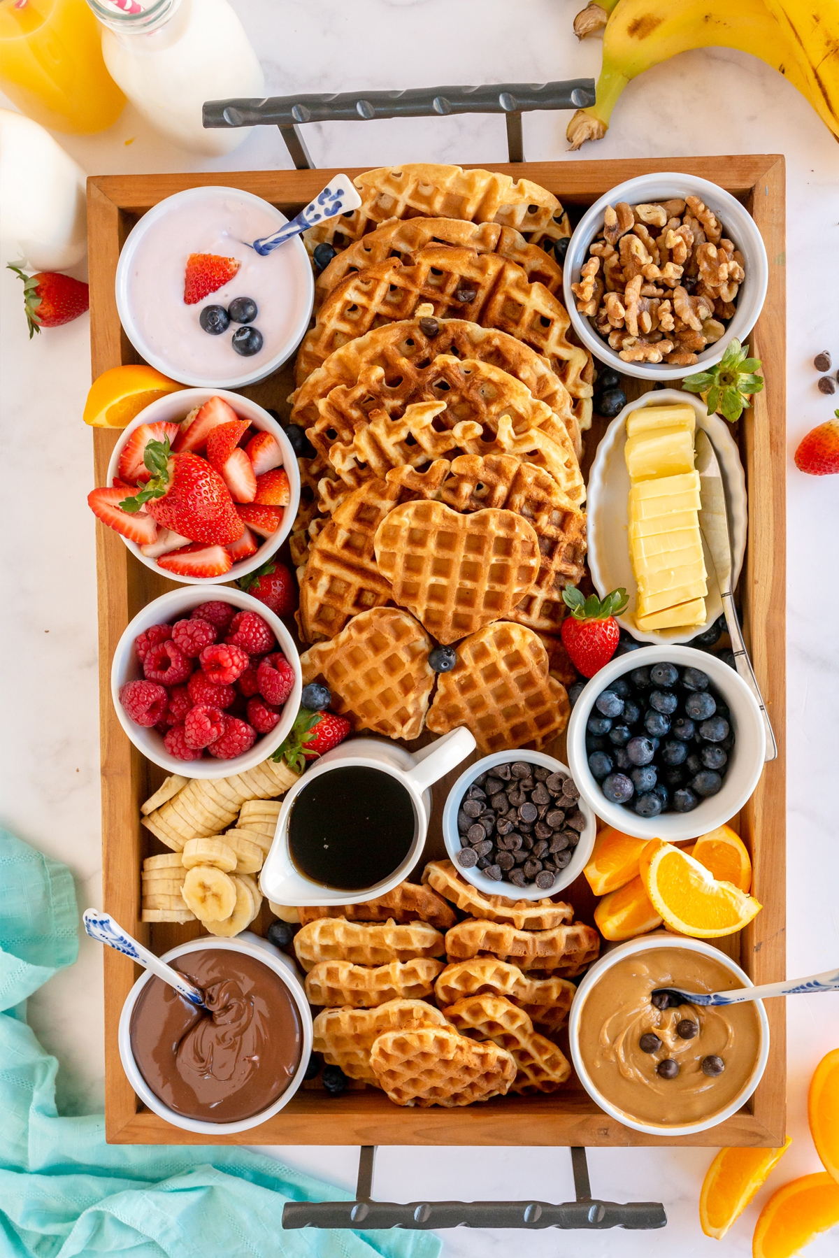 a mixture of large and small waffles surrounded by toppings like fruit, peanut butter, and syrup from made to be a momma.