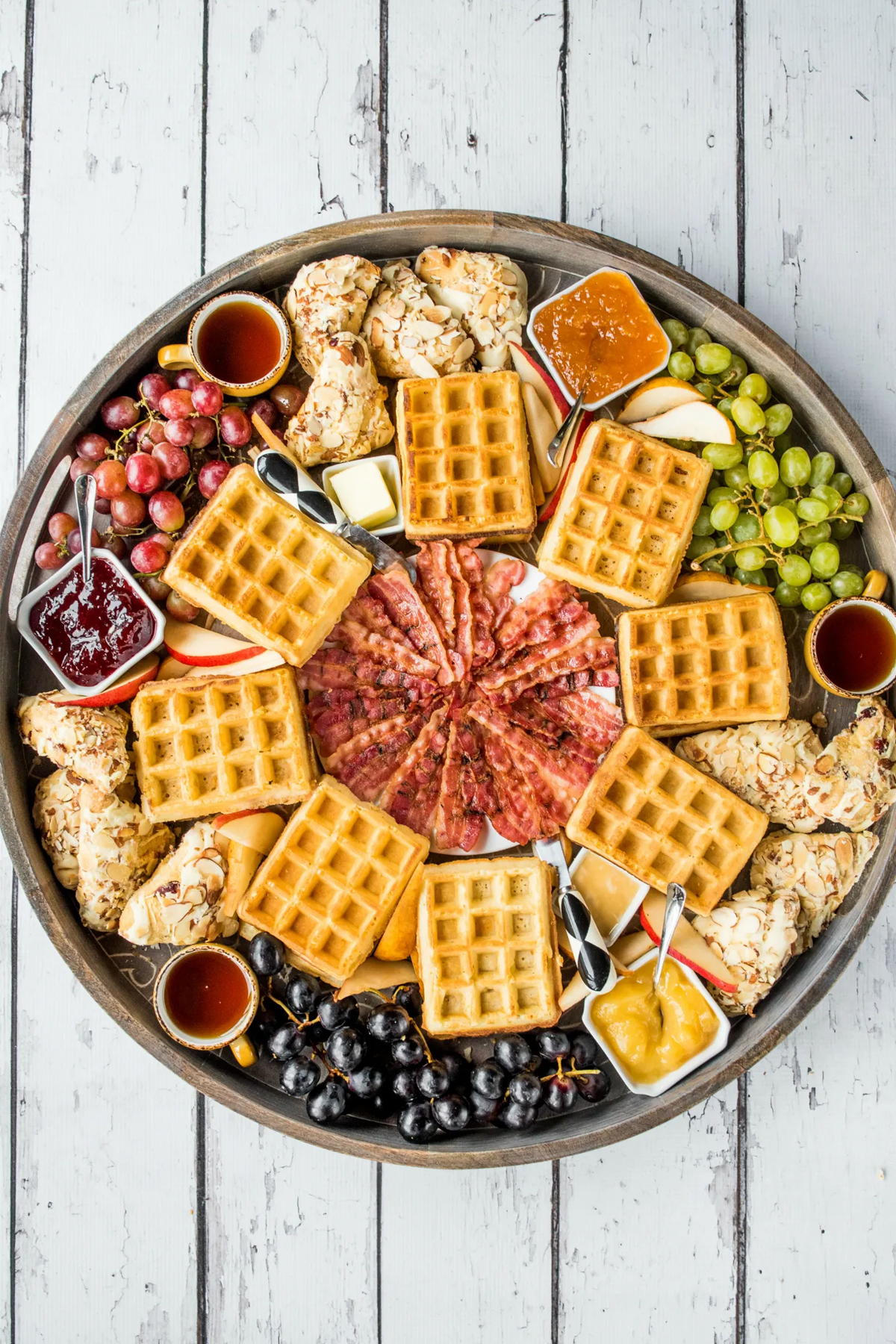a round waffle board full of waffles, fruit, and breakfast meats from reluctant entertainer