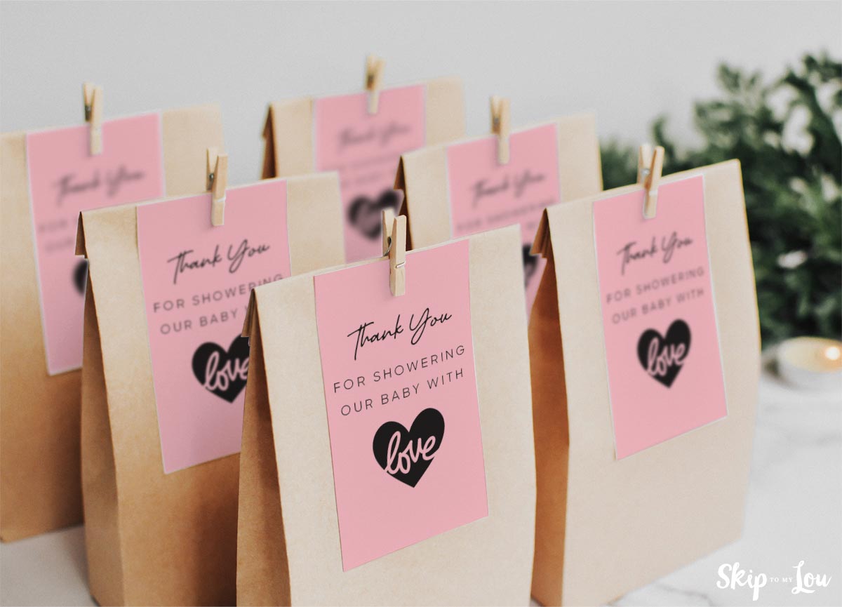 Baby shower gift tags placed on top of baby shower favor bags.