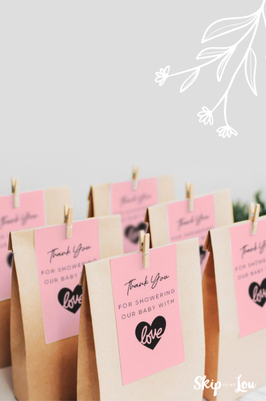 Baby shower gift tags placed on top of baby shower favor bags.