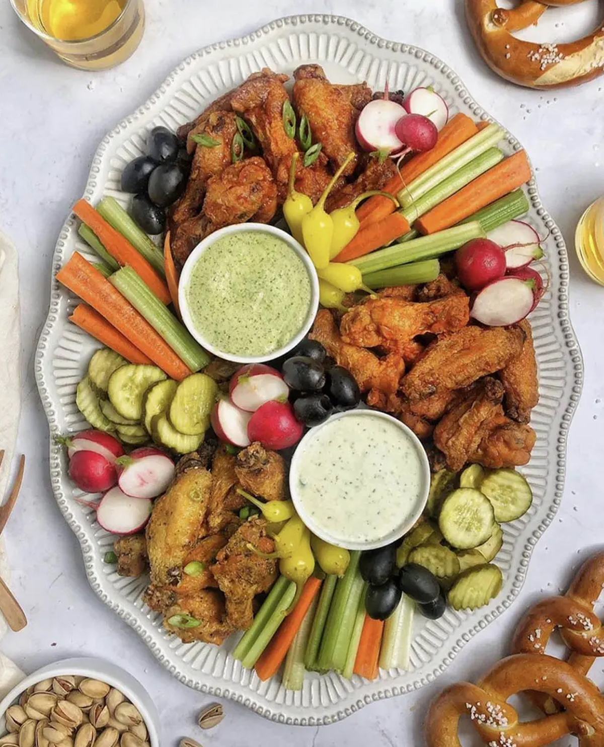Ain't Too Proud To Meg's board shows wings, dip, olives, carrots, and celery.