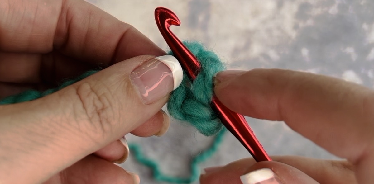 How to make a slip knot using a crochet hook, step 2, put the hook through and start pulling it back