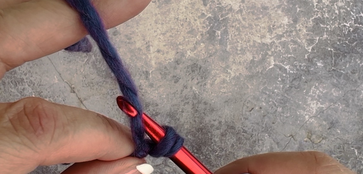 First step to create a chain crochet - hold the piece with your middle finger and thumb