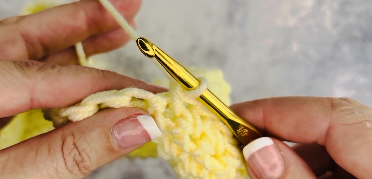 Step 2 to make a stitch crochet, Insert your crochet hook under the stitch underneath.