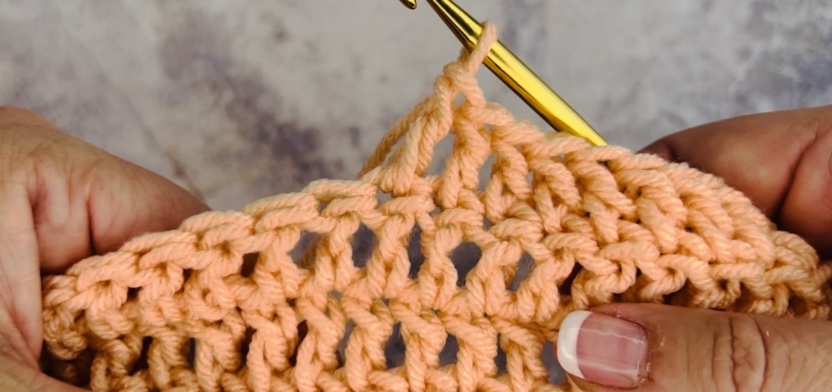 First step to do a double crochet with salmon-colored yarn.