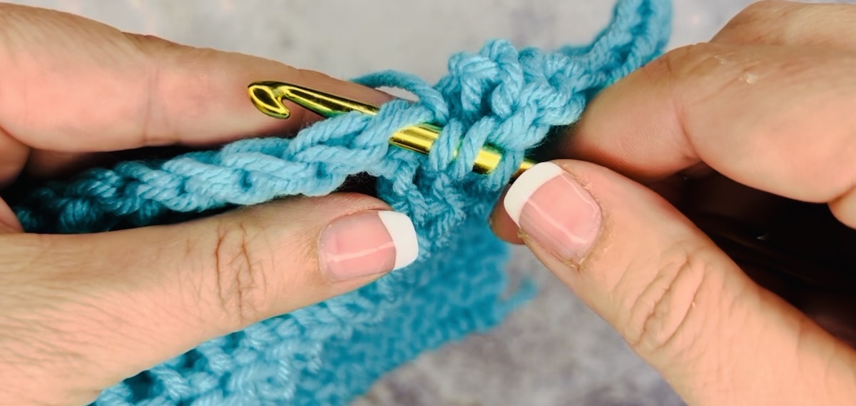 Step 2 to do a treble crochet: insert hook under two loops