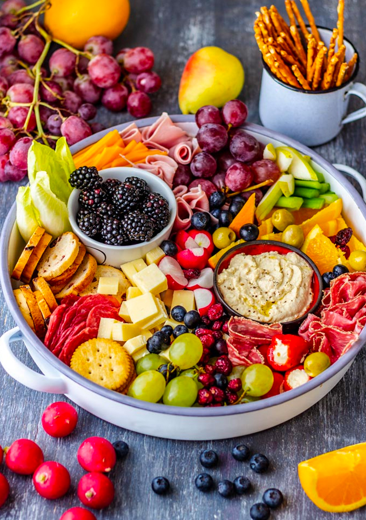 An assortment of cheeses, meats, fruit, olives, and crackers are filling Appetizer Addiction's winter cheese board.