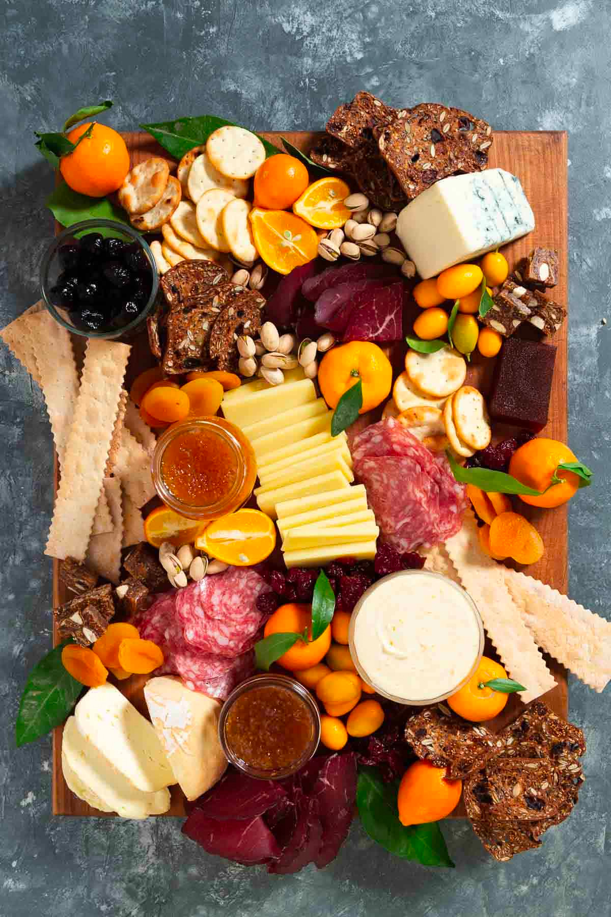 Cup of Zest winter cheese and meat board is complete with meat, cheese, oranges, nuts, crackers, and jelly.