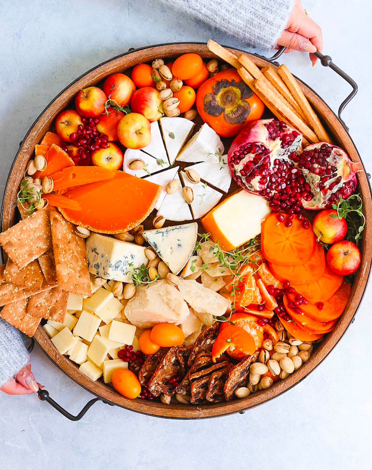Damn Delicious's cheese board is complete with pomegranates, cheese, nuts, seasonal fruit, and crackers.