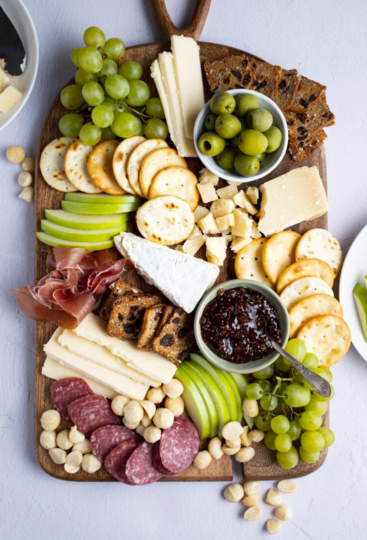 Grapes, bread, meat, cheese, nuts, and clementines fill Yoga of Cookings winter cheese board.