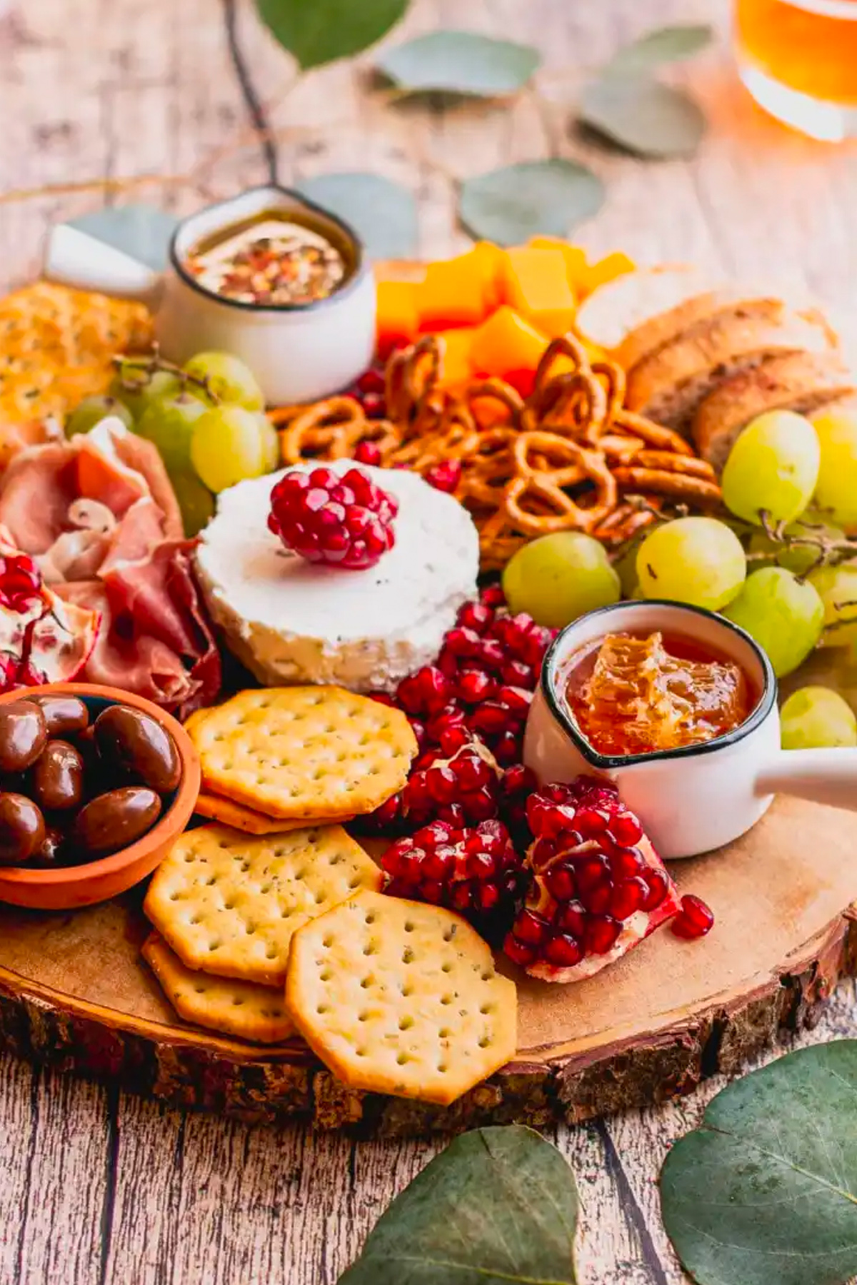 Sweet Tea and Thyme's board is filled with pomegranates, crackers, cheese, meat, grapes, and olives.