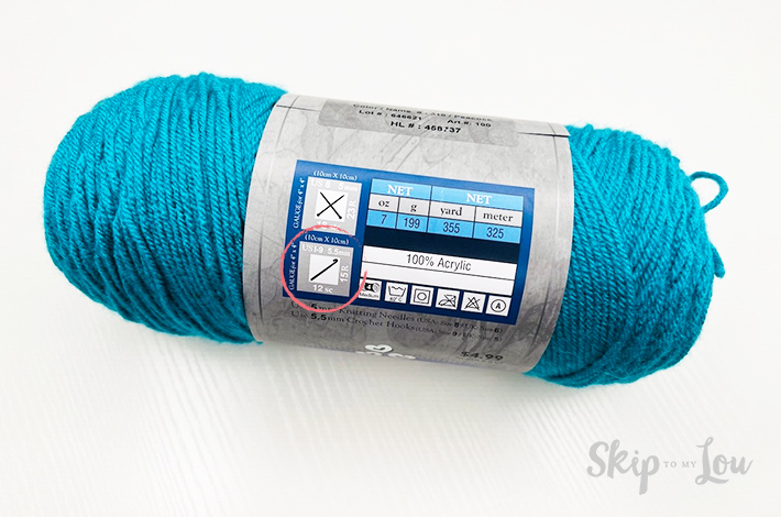 Blue yarn to make a granny square in a new package over a white background.