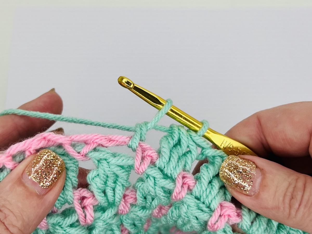 Mint green and light pink sample of cluster crochet stitches on a white background.