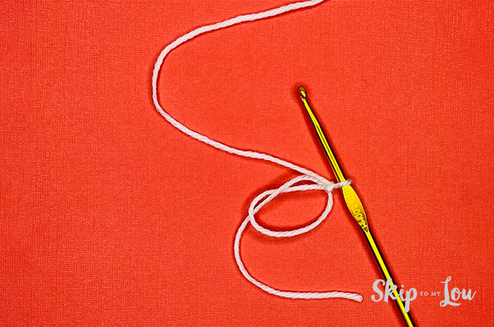 A white yarn loop(magic circle) on an orange background.