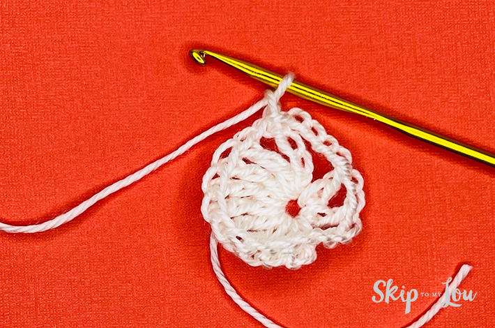 White yarn crocheted into a circle on an orange background.