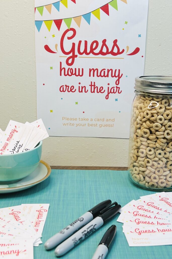 guess how many in the jar sign with a mason jar of cheerios, pens and cards for making guesses