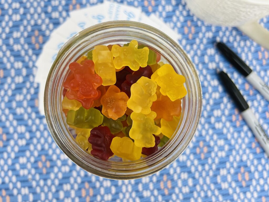 gummy bears in a quart mason jar with cards for guessing how many