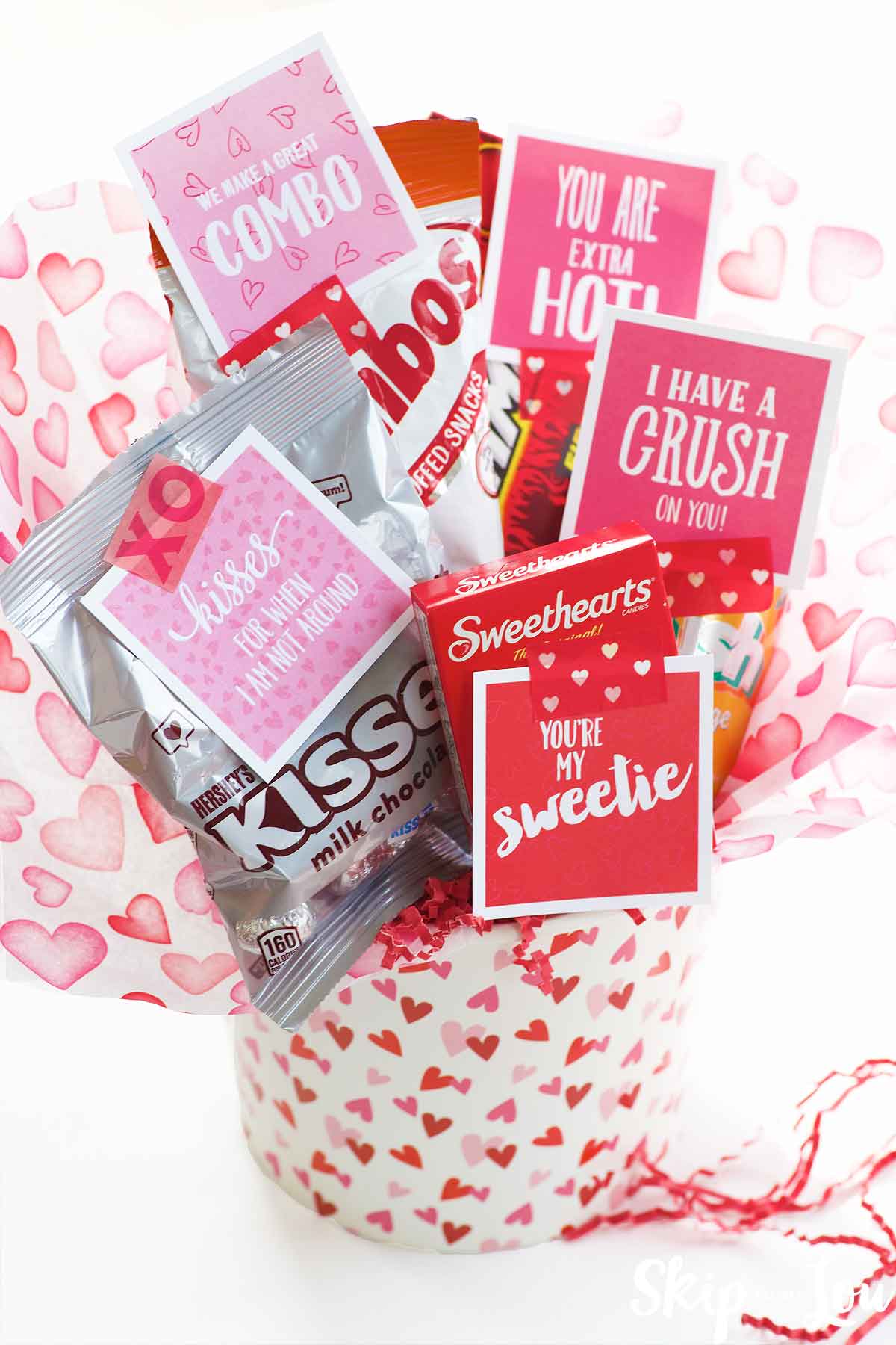 heart decorated bucket filled with candy with candy pun tags on each item