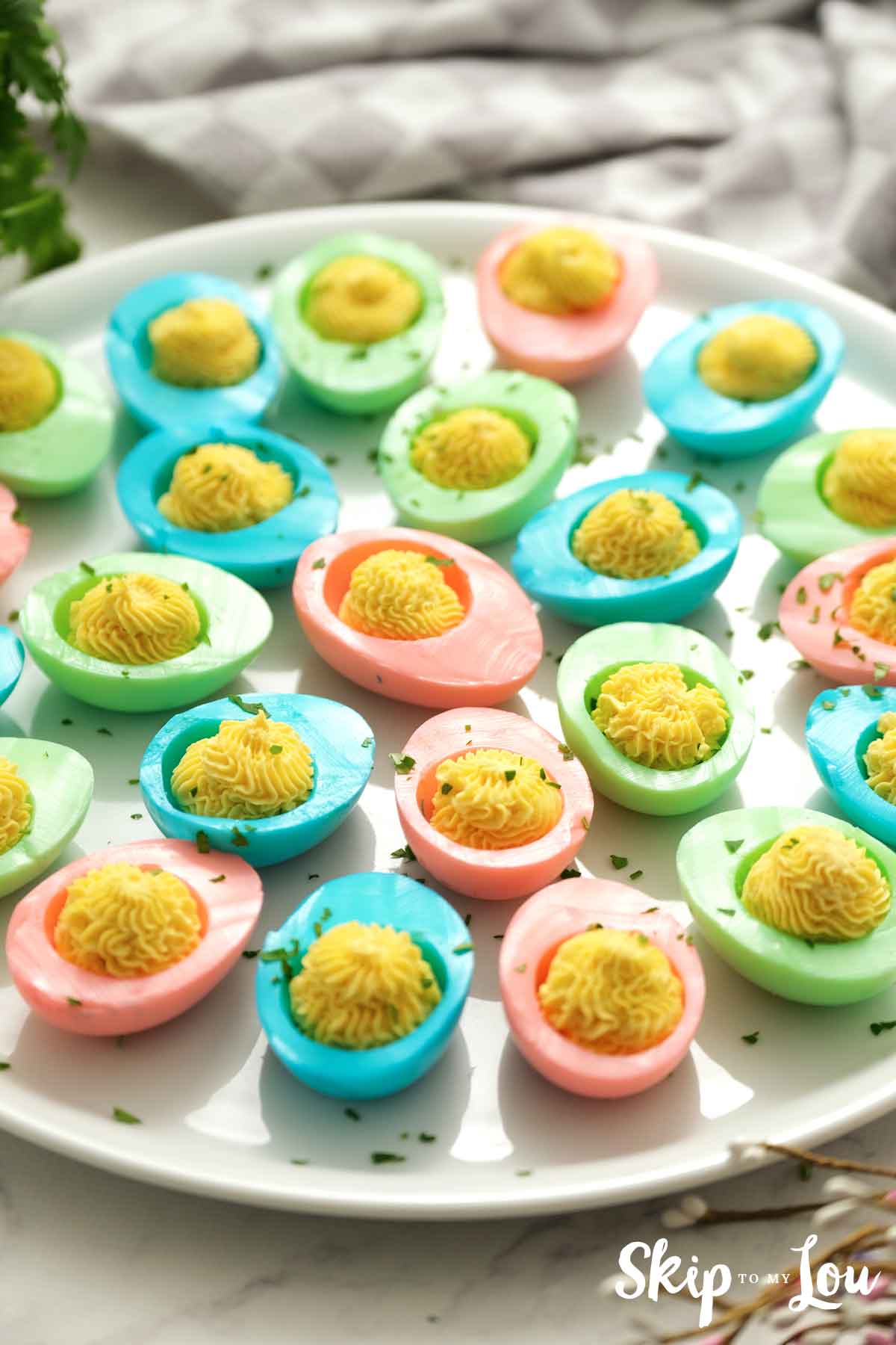 pink blue green colored deviled eggs on white platter
