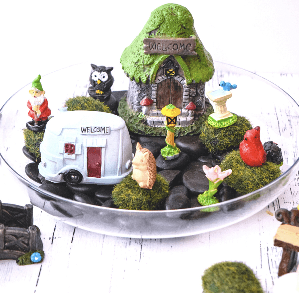 A fairy garden made in a glass bowl with various animals, a gnome, and two small fairy homes purchased from the dollar store. 