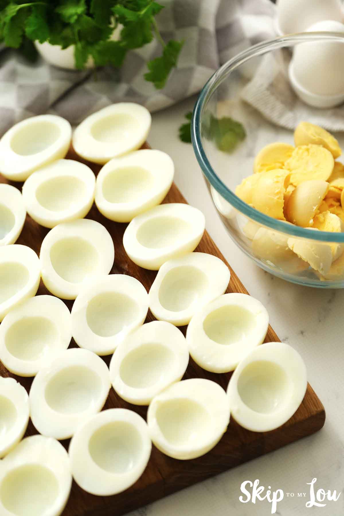 hard boiled eggs sliced in half with yolks removed on a cutting board