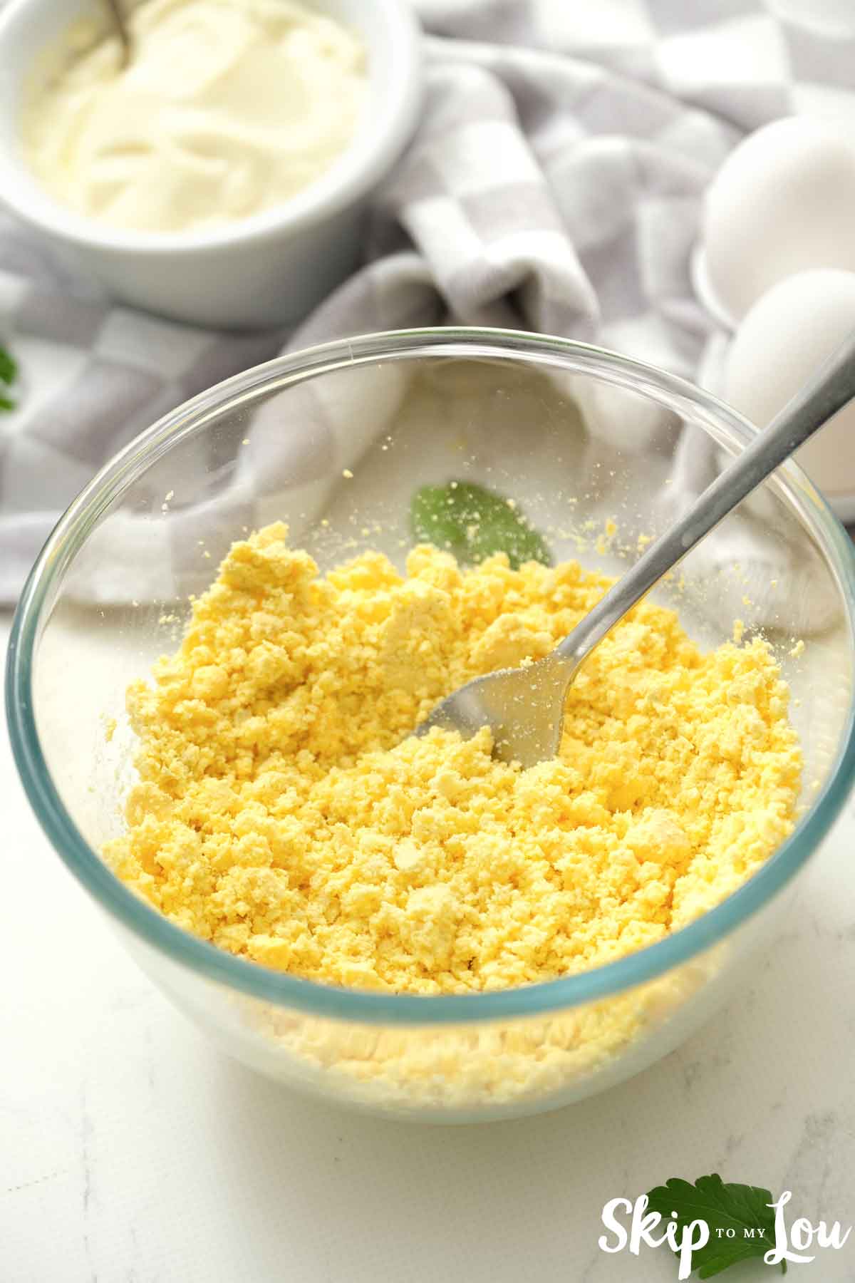 mash egg yolks in bowl