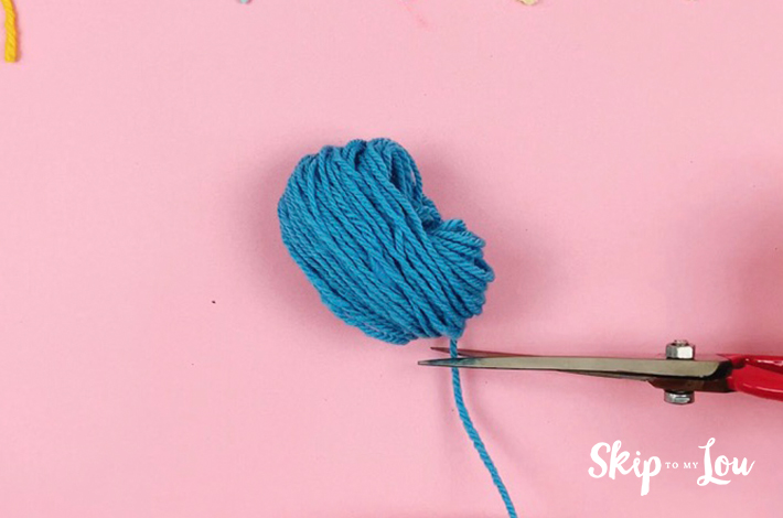 Cutting the pom pom from the ball of wool.