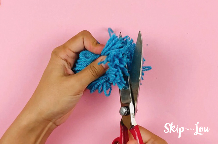 The tied ends of the pom pom are now cut.