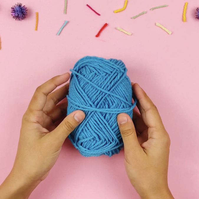 A blue ball of wool on a pink background